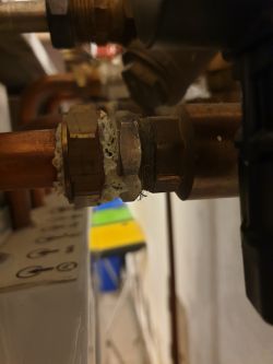 Fragment instalacji hydraulicznej z bliska, z widoczną uszczelką na rurze miedzianej.