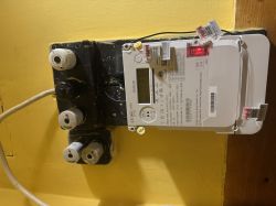 Licznik energii elektrycznej obok starej tablicy z bezpiecznikami ceramicznymi