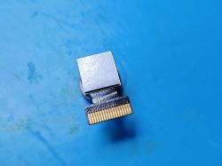 Mini Camera with 18-pin FFC ZIF Connector on a Blue Surface Mini camera module with 18-pin FFC ZIF connector, viewed from connector side, on a blue surface.