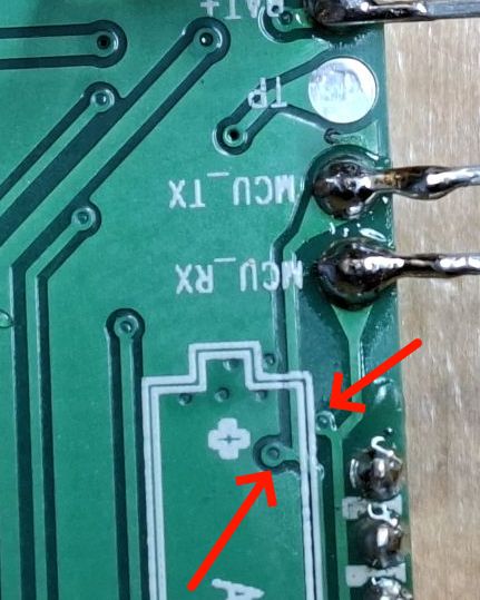 Section of green PCB labeled MCU_TX, MCU_RX with solder joints and red arrows