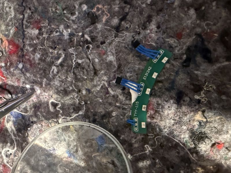 Zakrzywiona zielona płytka PCB z przewodami na szarej, włóknistej powierzchni
