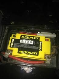 Żółty akumulator MOTOBATT z czerwonym i czarnym przewodem w komorze pod pokrywą