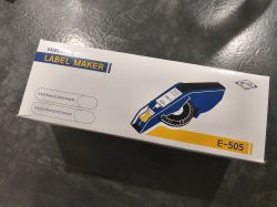 Box with Motex E-505 embossing label maker lying on a dark reflective surface