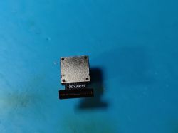 Metal electronic component with M7-39-V1 marking on a blue background.