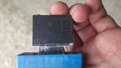 Zbliżenie na czarny włącznik elektryczny z oznaczeniami, trzymany w dłoni nad niebieską obudową