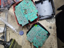 Two disassembled electronic devices on a workbench showing PCBs.