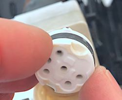 Zbliżenie na okrągły biały element ceramiczny z uszkodzeniem na krawędzi.