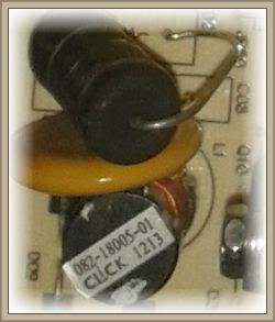 Zbliżenie na komponenty elektroniczne na płytce drukowanej, w tym cewkę, kondensator i element oznaczony etykietą „082-18005-01 CLICK 1213”.