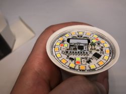 Close-up of an LED bulb's interior, held in a hand, showing diodes and a PCB.