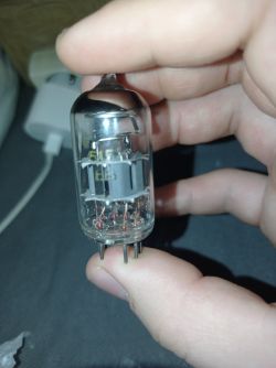 Lampa elektronowa w szklanej bańce trzymana w dwóch palcach