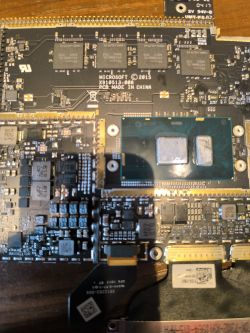 Zbliżenie na płytę główną Surface Book z widocznymi układami scalonymi.