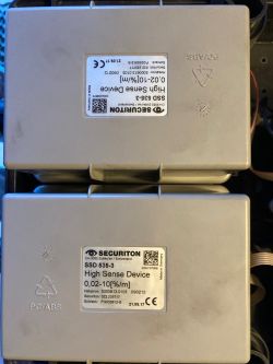 Dwa sensory zabezpieczeń Securiton SSD 535-3 z etykietami.