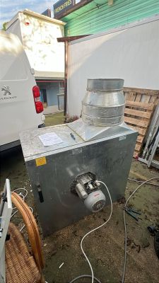 Wentylator przemysłowy z silnikiem elektrycznym i otwartą puszką przyłączeniową, ustawiony na zewnątrz obok narzędzi i instrukcji.