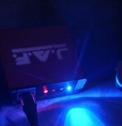 Zbliżenie na urządzenie JAF Box z podłączonym kablem, z widocznymi czerwonymi i niebieskimi diodami LED.