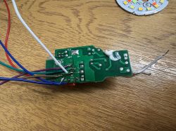 PCB with multicolored wires soldered, placed on wooden surface with LED module nearby