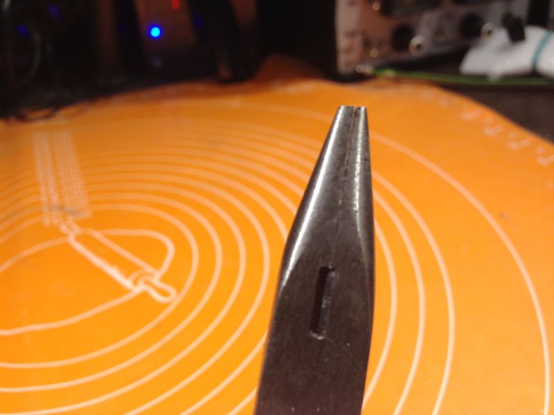 Bliskie ujęcie szczypiec z wąską końcówką na pomarańczowym tle