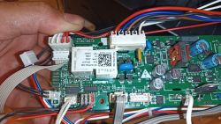 Zbliżenie na płytę główną urządzenia elektronicznego trzymaną w ręce, z widocznymi przewodami i komponentami elektronicznymi.