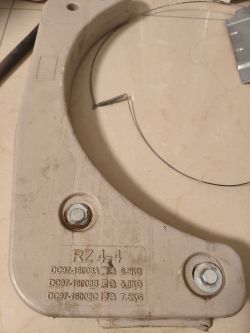 Ciężarek z pralko-suszarki Samsung, wykonany z szarego materiału, z widocznym oznaczeniem modelu i zamocowanymi śrubami oraz sprężyną z drutem.