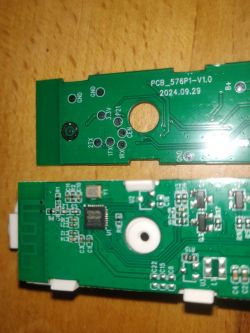 Two green circuit boards with various markings and components on a wooden surface.