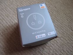 Sonoff Type G Wi-Fi Smart Plug Packaging Box of Sonoff Type G Wi-Fi Smart Plug on a beige carpet.