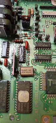 Zbliżenie na płytkę drukowaną z różnymi elementami elektronicznymi, na której widoczny jest element oznaczony jako E4VF-AA NDK 8644.
