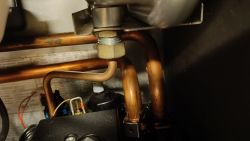 View of the plumbing inside a boiler with visible copper pipes and fittings.