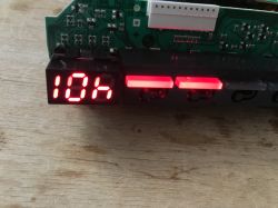 Wyświetlacz 7-segmentowy LED i podświetlane wskaźniki na płytce PCB programatora zmywarki, świecące na czerwono.
