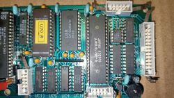 Zbliżenie na płytę drukowaną z widocznymi komponentami elektronicznymi i oznaczeniami.