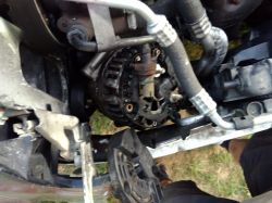 Alternator w samochodzie, otoczony rurkami i przewodami, częściowo zdemontowany.