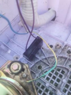 Zbliżenie na przewody elektryczne i silnik elektryczny zamontowane w plastikowej obudowie urządzenia.