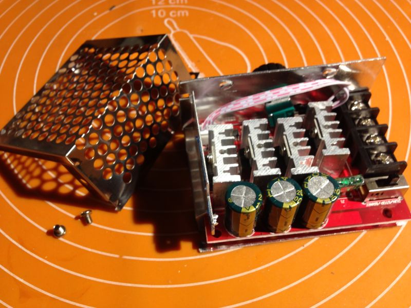 Rozebrany regulator PWM z widocznymi radiatorami, kondensatorami i obudową perforowaną.