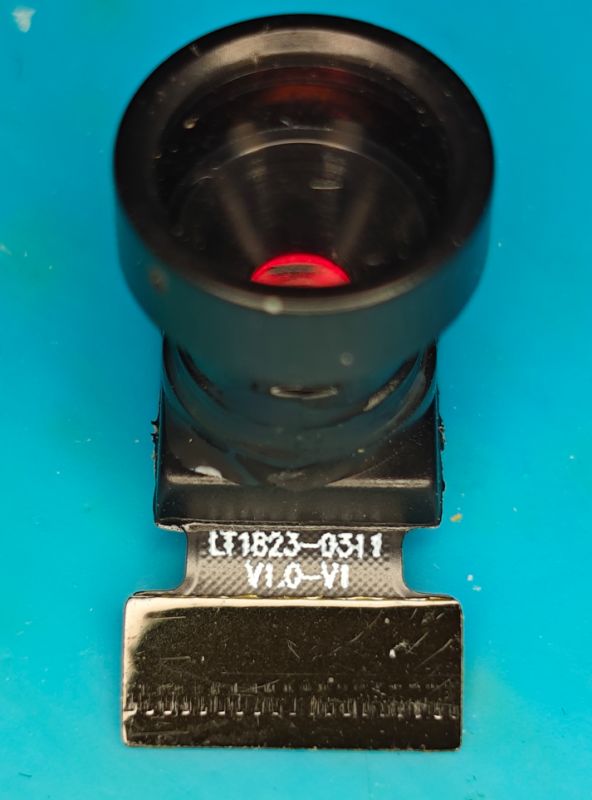 Camera module with lens and ribbon connector on blue background