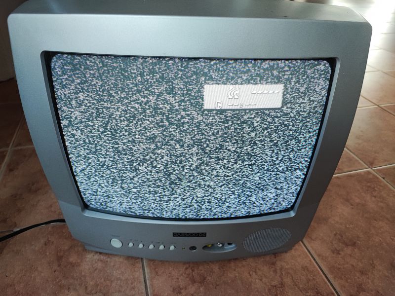 Telewizor kineskopowy Daewoo K14C5GT z wyświetlaczem pokazującym statyczny obraz na tle płytek podłogowych.