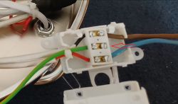 Zbliżenie na kostkę elektryczną z podłączonymi przewodami: brązowym, niebieskim, zielono-żółtym i czerwonym