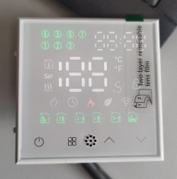 Glass thermostat control panel with backlit 28.2°C display and mode icons