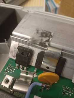 Zbliżenie na tranzystory IGBT oraz radiator w płycie indukcyjnej, widoczna biała płytka izolacyjna posmarowana pastą termoprzewodzącą.