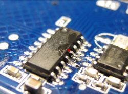 Close-up of an integrated circuit mounted on a blue circuit board.