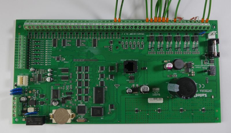 Zielona płyta główna systemu alarmowego z licznymi złączami i komponentami elektronicznymi