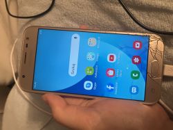 Telefon włączony z pękniętym ekranem i otwartą listą aplikacji.