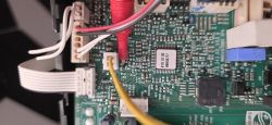 Zbliżenie na płytkę PCB z podłączonymi przewodami pomiarowymi multimetru.