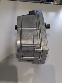 Srebrny silnik elektryczny BROSE do roweru widoczny z boku na jasnym blacie.