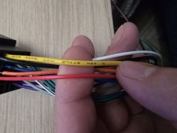 Przewody zasilające ISO do radia 2 DIN w VW Polo 4, pokazujące różne kolory kabli w ręce użytkownika.