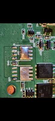Zbliżenie na płytkę drukowaną z uszkodzonymi elementami elektronicznymi.
