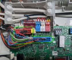 Close-up of an electronic board with multiple wires and connectors marked in green.