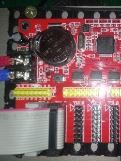 Zbliżenie na czerwoną płytkę PCB z elementami elektronicznymi, w tym bateria CR2032.