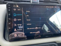 Ekran dotykowy w samochodzie pokazujący menu ustawień z różnymi opcjami, takimi jak Wi-Fi, GPS i dźwięk.