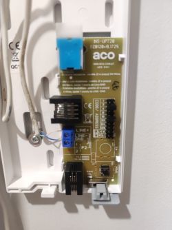 Wnętrze urządzenia domofonowego z widocznym obwodem elektronicznym i podłączonymi przewodami.