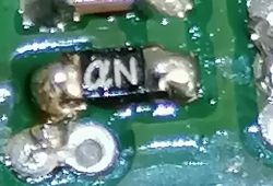 Zbliżenie elementu SMD oznaczonego literami QN na zielonej płytce PCB