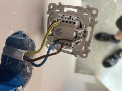 Włącznik elektryczny z podłączonymi trzema przewodami: brązowym, niebieskim i żółto-zielonym.