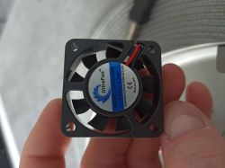 Mały wentylator UltraFan 5 V w czarnej ramce, trzymany w palcach, widoczna etykieta modelu.